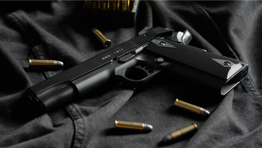A black pistol and bullets are laid out on black fabric.