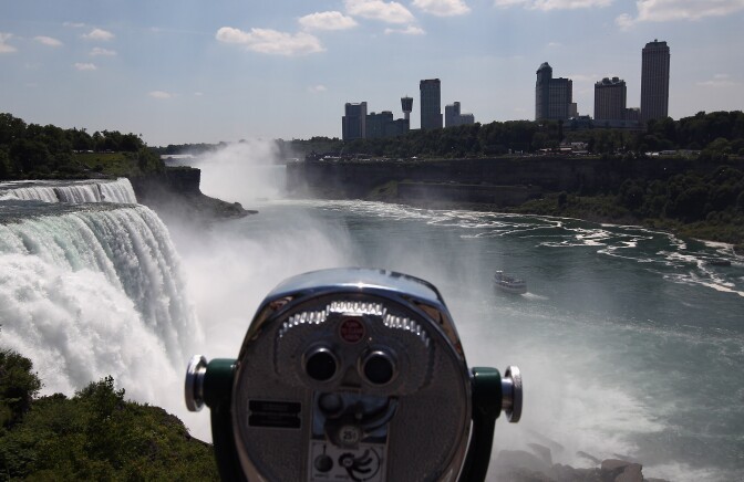 A tour boat heads past Niagara Falls on the U.S.-Canada border June 15, 2012 as seen from from Niagara Falls, New York. Aerialist Nik Wallenda will attempt walk across a 1,800 foot 2 inch-wide wire Friday night as the first person to attempt to cross directly over the falls from the U.S. into Canada. Wallenda, 33 and a father of three, is a seventh generation member of the famed Flying Wallendas who trace their roots to 1780 Austria-Hungary, when ancestors traveled as a band of acrobats, aerialists, jugglers, animal trainers and trapeze artists. ABC is televising the event at 10:15pm Eastern Time Friday and insisted the daredevil wear a teathered harness to prevent live coverage of a potentially deadly fall 190 feet into the churning torrent below. 