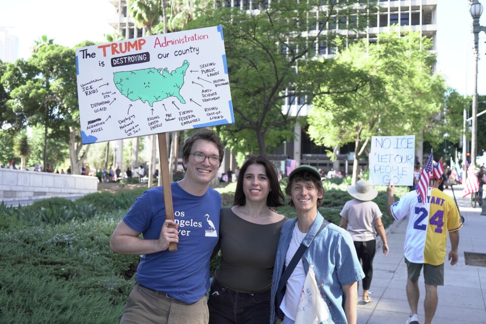 A sign says: the Trump administration is destroying our country and then notes a range of issues.