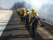 Rio Hondo College Wildland Fire Academy's Fire Crew 77, nicknamed the Roadrunners, hike along the 14 Freeway to help fight a brushfire in the Saugus Ranger District in Santa Clarita on July 12, 2015.