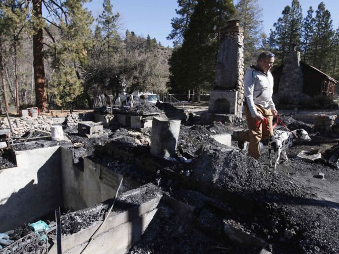 Rick Heltebrake with his dog Suni looks over the burned-out cabin where Christopher Dorner's remains were found after a police standoff Tuesday near Big Bear, Calif., Friday Feb. 15, 2013. Earlier, Heltebrake had been carjacked by Dorner.