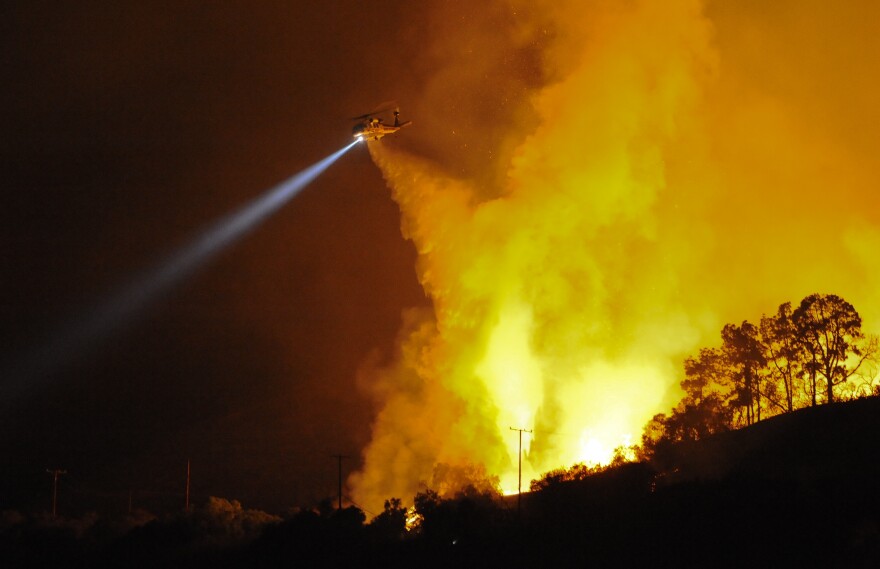 A firefighting helicopter drops water after at least six homes were destroyed by a fast moving brush fire that broke out in Rancho Palos Verdes, Calif., shortly after 8:00 p.m., Thursday, Aug. 28, 2009.