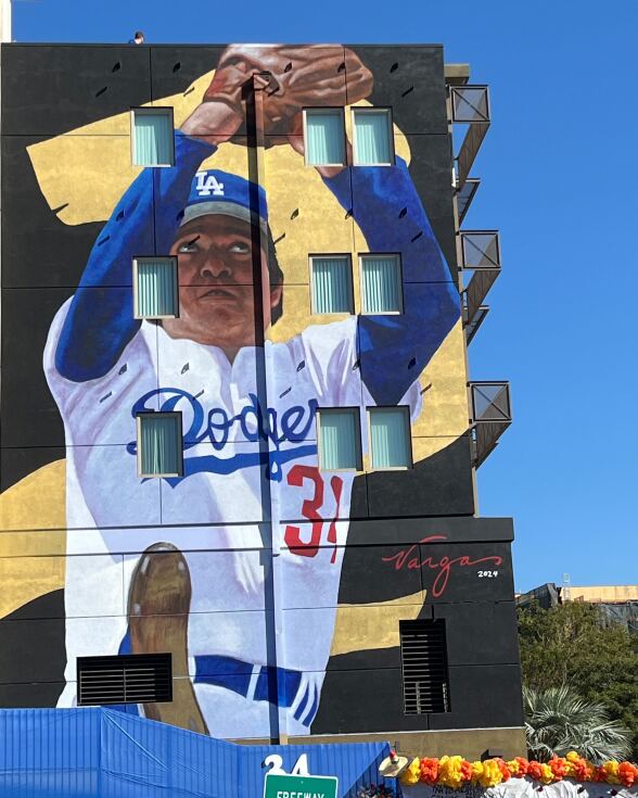 A giant mural of a baseball pitcher on a wall.
