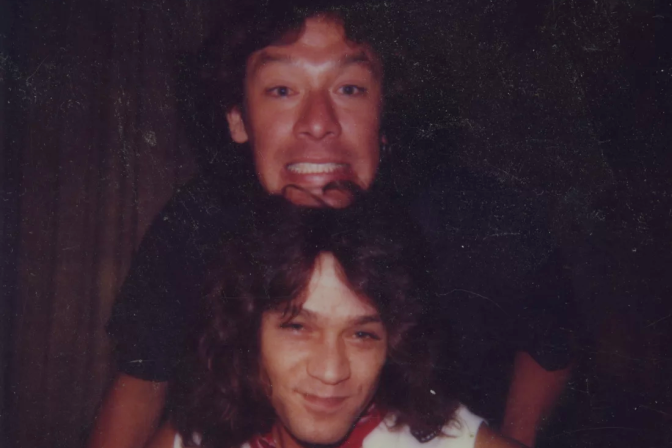 A photograph of two people with one's head on top of the other's as they pose