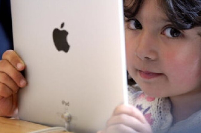 A young girl holds an Apple iPad. 