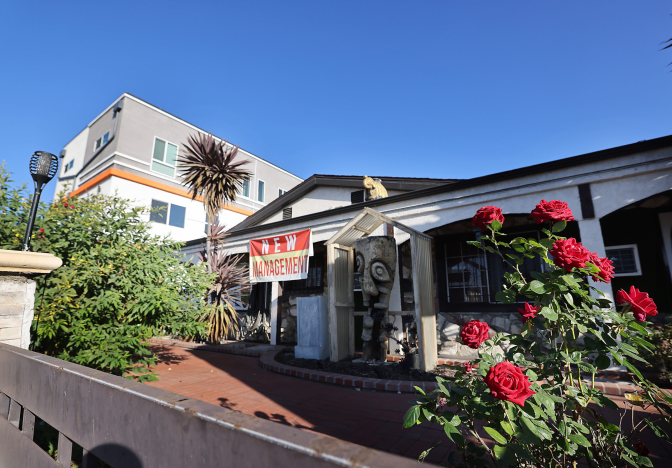 A one-story building with a red and white sign that reads new management