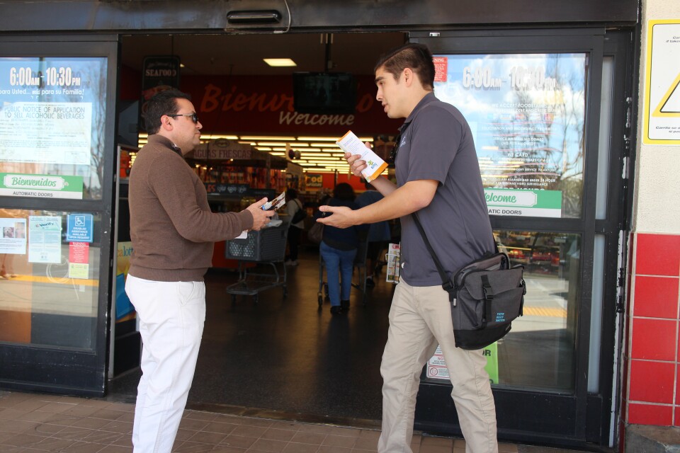 Matthew Fontana, a promotor with the Youth Policy Institute, talks with a shopper outside of the Northgate Market in Culver City. 