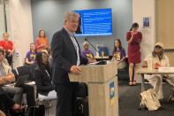 A man in a suit stands at a podium. 