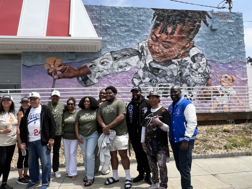 Robert Vargas takes a picture with other Altadenans and local supporters in front of his new mural "From The Ashes" at Fair Oaks Burger.