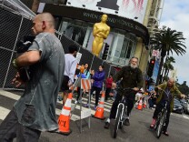 Hollywood Boulevard at Highland Avenue in Hollywood, California is closed off to the public as pedestrians pass a large statue of the Oscar on display on February 21, 2015, with one day to go before the 87th annual Academy Awards takes place along Hollywood Boulevard and at the Dolby Theater. AFP PHOTO / FREDERIC J. BROWN        (Photo credit should read FREDERIC J. BROWN/AFP/Getty Images)