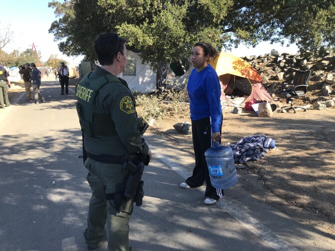 Orange County sheriff's deputy Molly Mussig talks to a resident about moving off of the Santa Ana riverbed on Monday, January 22, 2018.