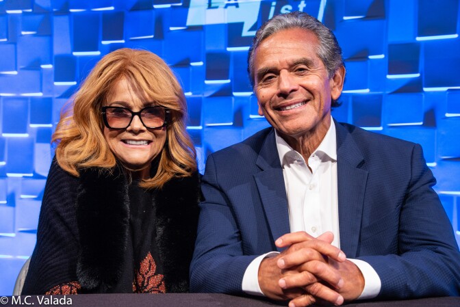 Ann-Margret, a white woman wearing glasses and a black top and Antonio Villaraigosa, a Hispanic man with gray hair wearing a navy suit jacket and white shirt, smiling at the camera