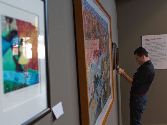 Julian Bermudez hangs an exhibition of Chicano art in KPCC's Crawford Family Forum ahead of an Airtalk special on Wednesday.