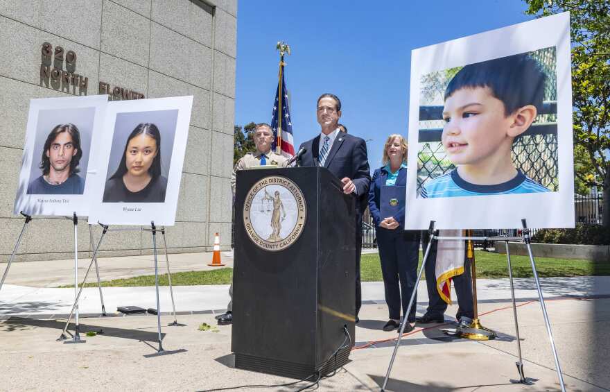 Large photos flank a lectern where Orange County DA Todd Spitzer speaks. At the right is an image of Aiden Leos, 6, in partial profile. At the left are mugshots of Wynne Lee and Marcus Eriz.