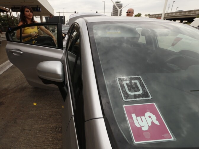 A passenger gets into a car marked as participating in both Uber and Lyft.