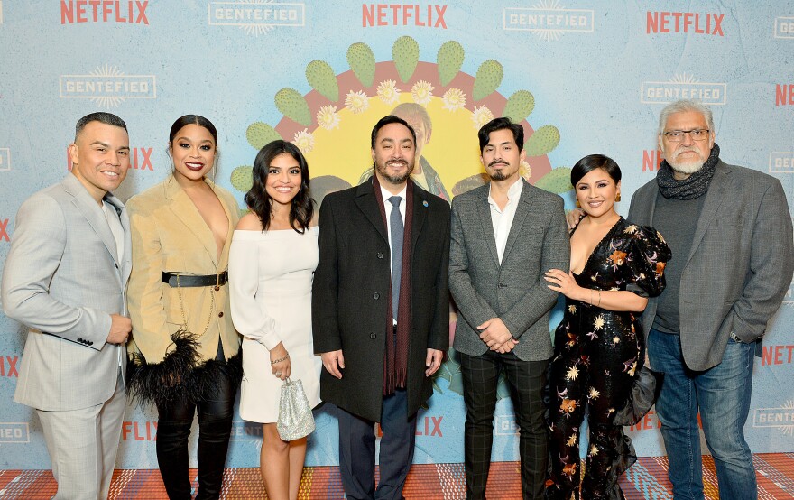 Seven people pose in a in in front of backdrop for Gentefied.