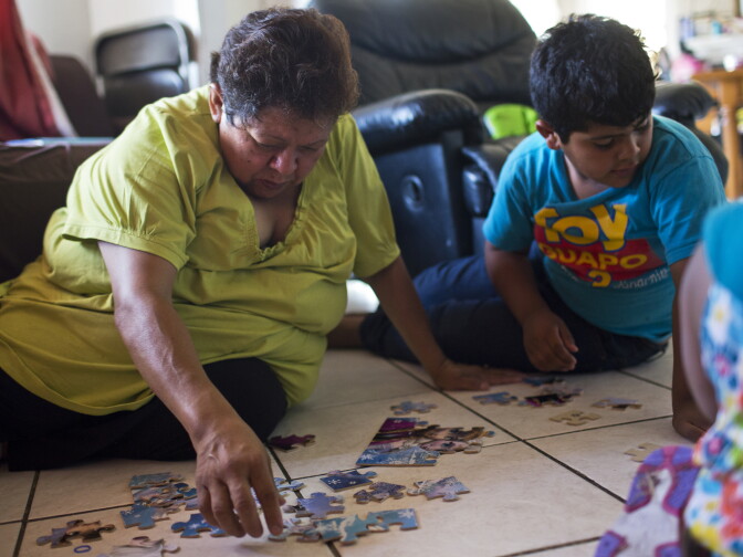 Maria Garcia, 58, left, puts a puzzle together with her grandson, Pablo Andres Garcia, 6, in their South Los Angeles home on Monday afternoon, August 3, 2015.