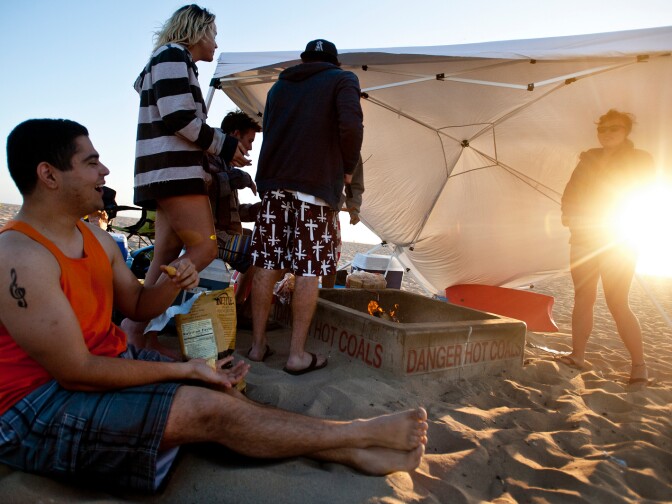 Toby Bender of Lakewood, left, and his friends have a bonfire on Thursday evening, June 6. Officials from the California Coastal Commission say the fire pits are a tradition and an important free amenity at Southern California beaches.