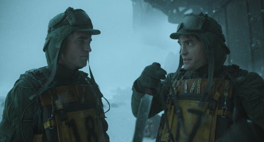 two men standing with hoodies on is snowy weather. one is holding a large knife