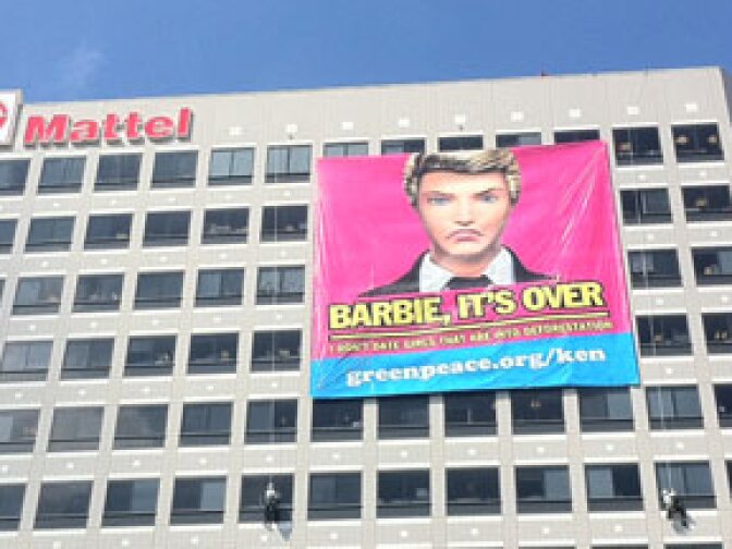 Greenpeace protesters hang a banner of Ken protesting Mattel's actions in the Indonesian rainforest at a Mattel office building.