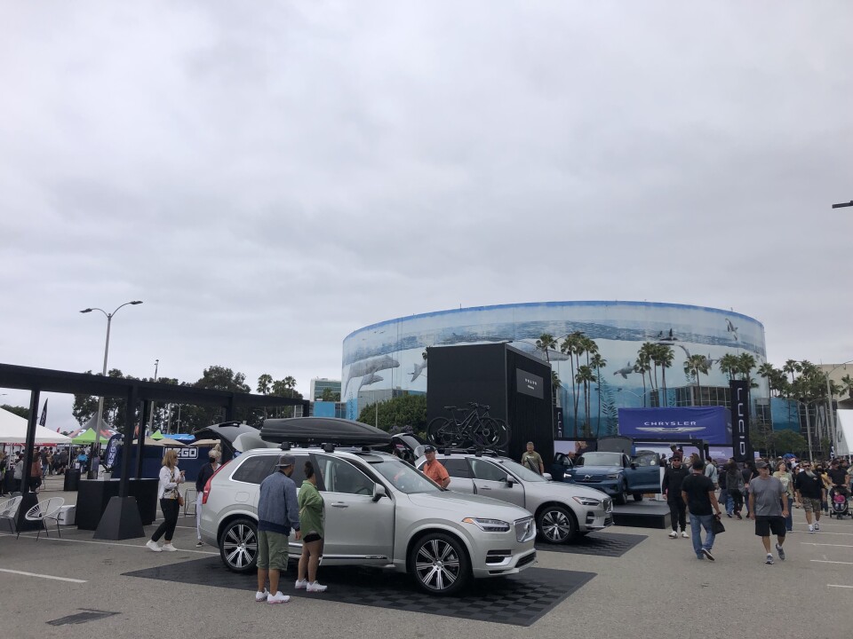A wide shot of a large parking lot with electric vehicles and people walking around.