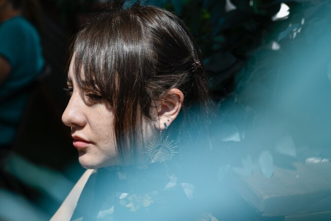 A woman wearing sunburst earrings is photographed in profile in sunlight.