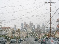 View of the downtown Los Angeles skyline from behind a rain-soaked car windshield.