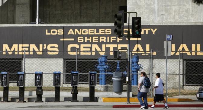 FILE - In this Sept. 28, 2011 photo, people walk past the Los Angeles County Sheriff's Men's Central Jail facility in Los Angeles. A federal judge has given initial approval to an agreement that requires the Los Angeles County Sheriff’s Department to improve conditions in its jails for inmates using wheelchairs and others with mobility impairments. (AP Photo/Damian Dovarganes, File)