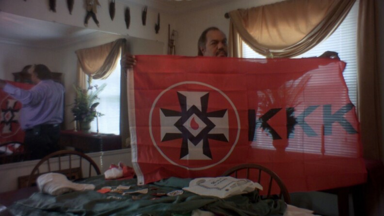 Daryl Davis displays KKK flag.