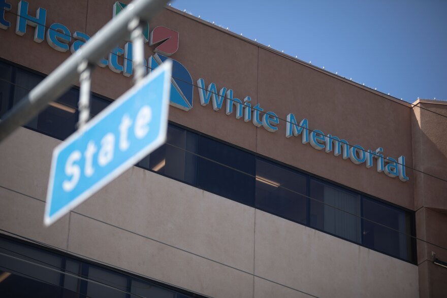 The exterior of a multi-story medical center building is in the background. The signage reads White Memorial. There is also a street sign in the frame for State Street.