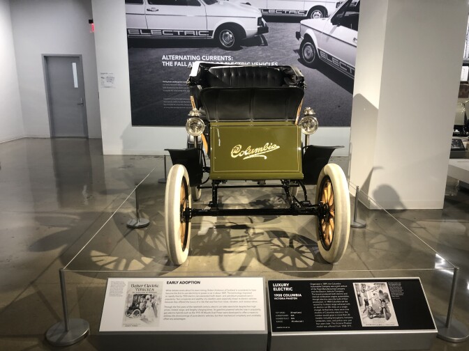 An image of the front of one a green automobile with black leather seating and white wheels. 