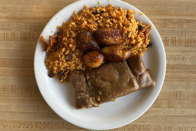 Puerto Rican Pastelle sits on a white plate next to a helping of rice with fried plantains 