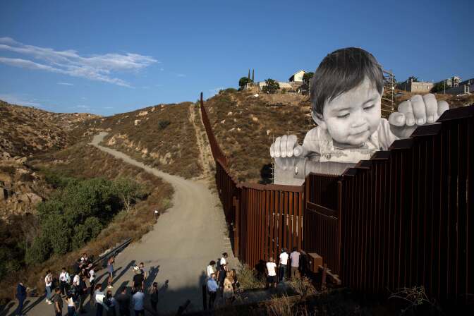 People attend the inauguration of an artwork by French artist JR on the US-Mexico border in Tecate, California, United States on September 6, 2017.