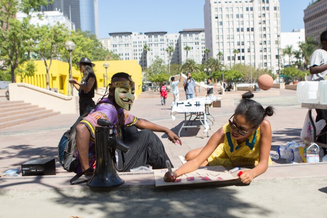 Esho Funi, left, watches Kandist Mallet, right, make signs for occupiers on the one year anniversary of Los Angeles' Occupy movement in Los Angeles, Calif., Monday, October 1, 2012. More than 300 protestors gathered at Pershing Square to celebrate and march around downtown.