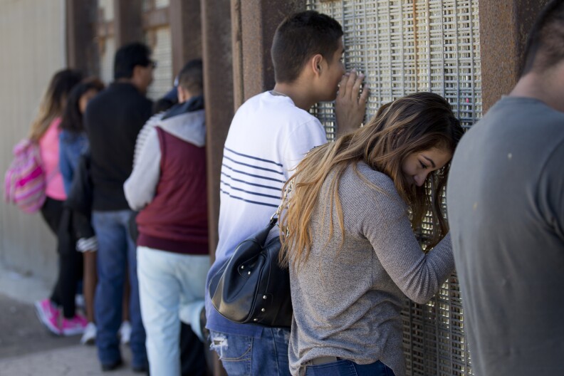 In this May 1, 2016 picture, Eva Lara, second from right, reacts as she reaches for her grandmother Juana Lara through the border wall during a brief visitation near where Mexico and the United States meet at the Pacific Ocean in San Diego. Lara, who lives in the United States legally through legislation that temporarily prevents young immigrants from being deported, has not seen her grandmother since the family left Mexico when she was three years old. (AP Photo/Gregory Bull)