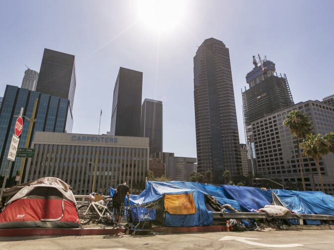 Tents used by the homeless line a downtown Los Angeles street with the skyline behind Tuesday, Sept. 22, 2015.