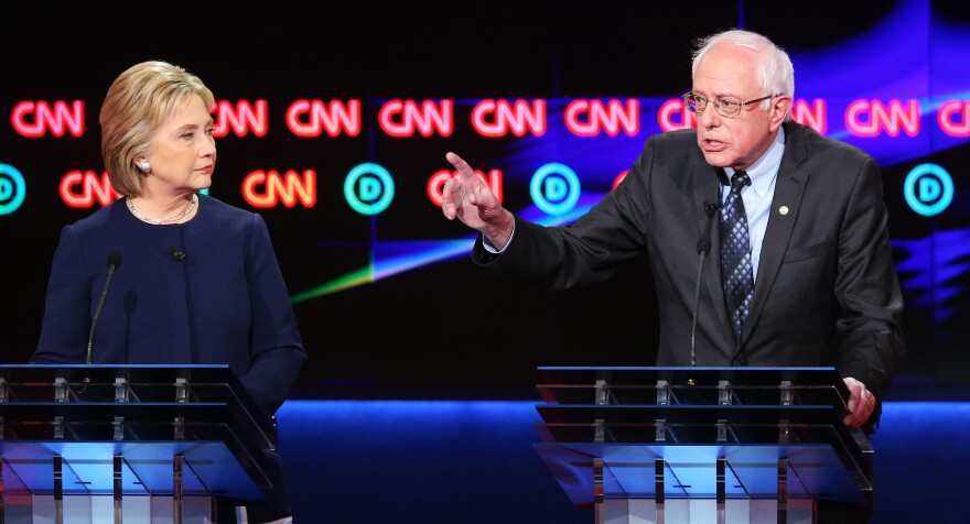 FLINT, MI - MARCH 06:  Democratic presidential candidate Senator Bernie Sanders (D-VT) and Democratic presidential candidate Hillary Clinton speak during the CNN Democratic Presidential Primary Debate at the Whiting Auditorium at the Cultural Center Campus on March 6, 2016 in Flint, Michigan. Voters in Michigan will go to the polls March 8 for the state's primary.  (Photo by Scott Olson/Getty Images)