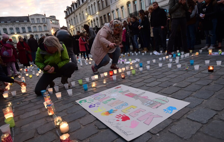 Persons light candles during a candle light vigil to the victims of the Paris attacks in Brussels' Molenbeek district, on November 18, 2015.