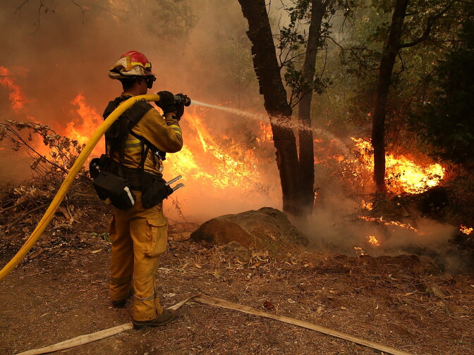 GROVELAND, CA - AUGUST 21:  A firefighter from Ebbetts Pass Fire District uses a hose to cool down hot spots of  back fire as he battles the Rim Fire on August 21, 2013 in Groveland, California. The Rim Fire continues to burn out of control and threatens 2,500 homes outside of Yosemite National Park. Over 400 firefighters are battling the blaze that is only 5 percent contained.  (Photo by Justin Sullivan/Getty Images)