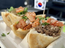 Photo of three pancakes, filled with different meats. They sit all side-by-side in a special tray. There's a small South Korean flag next to the food.