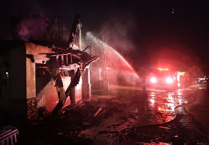 Firefighters hose down a burning house during the Tick Fire in Agua Dulce near Santa Clarita, California on October 25, 2019. - California firefighters battled through the night to contain a fast-moving wildfire driven by high winds that was threatening to engulf thousands of buildings. Around 40,000 people were told to flee the Tick Fire, which was raging across 4,000 acres (1,600 hectares) just north of Los Angeles. (Photo by Mark RALSTON / AFP) (Photo by MARK RALSTON/AFP via Getty Images)