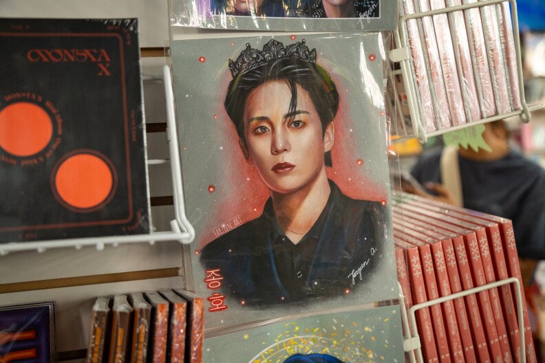 An Asian presenting person is on a poster display with light brown hair. A light is visible on the right of the poster.