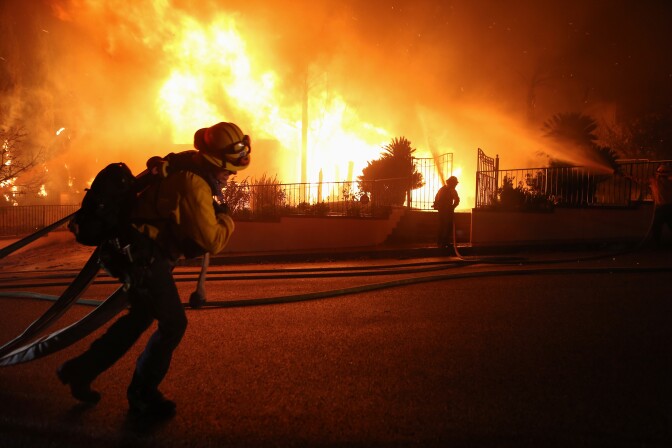 PORTER RANCH, CALIFORNIA - OCTOBER 11: Firefighters work on a house fire during the Saddleridge Fire in the early morning hours on October 11, 2019 in Porter Ranch, California. The fast moving wind-driven fire has burned more than 7,500 acres and destroyed 25 structures. (Photo by Mario Tama/Getty Images)