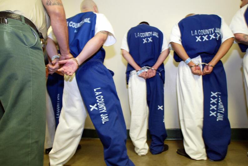 A deputy with the L.A. Sheriff's Department checks the handcuffs of prisoners.