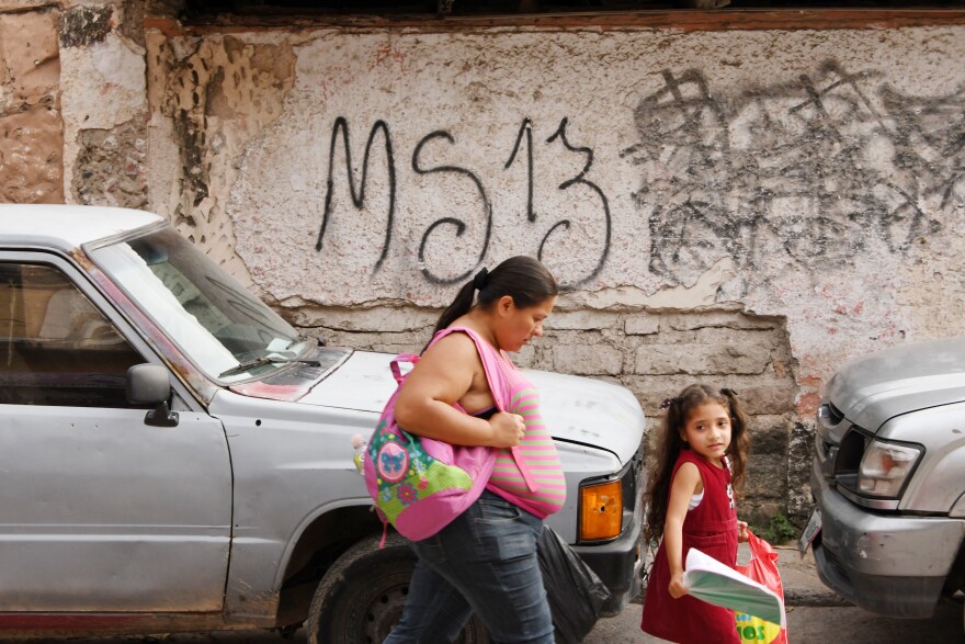 ocal residents pass by a grafitti made by the Mara Salvatrucha (MS-19) gang in the MS-13-controlled El Bosque neighborhood in Tegucigalpa, on May 9, 2017.
The territorial fight beweeen both rival gangs keeps the neighbors terrified. / AFP PHOTO / ORLANDO SIERRA / TO GO WITH AFP STORY BY NOE LEIVA        (Photo credit should read ORLANDO SIERRA/AFP/Getty Images)