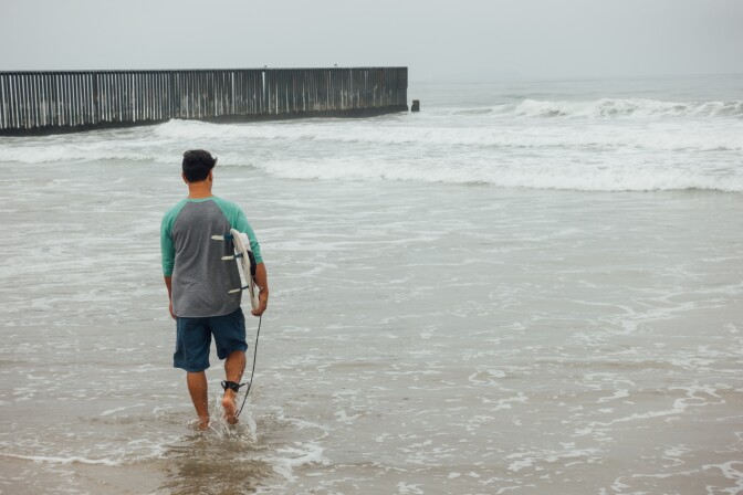 L.A. artist Diego Palacios heads out to surf at the border between the U.S. and Mexico on August 12th, 2017. The Beach at Border Field State Park in San Diego, CA is located in the farthest Southwest corner of the United States, separated from Playas de Tijuana by an 18-foot high fence.