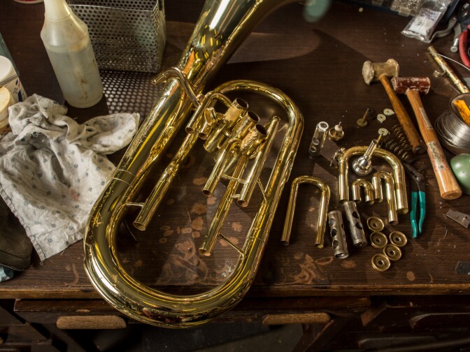 A baritone rests on the table of a technician in the early stages of the repair process.
