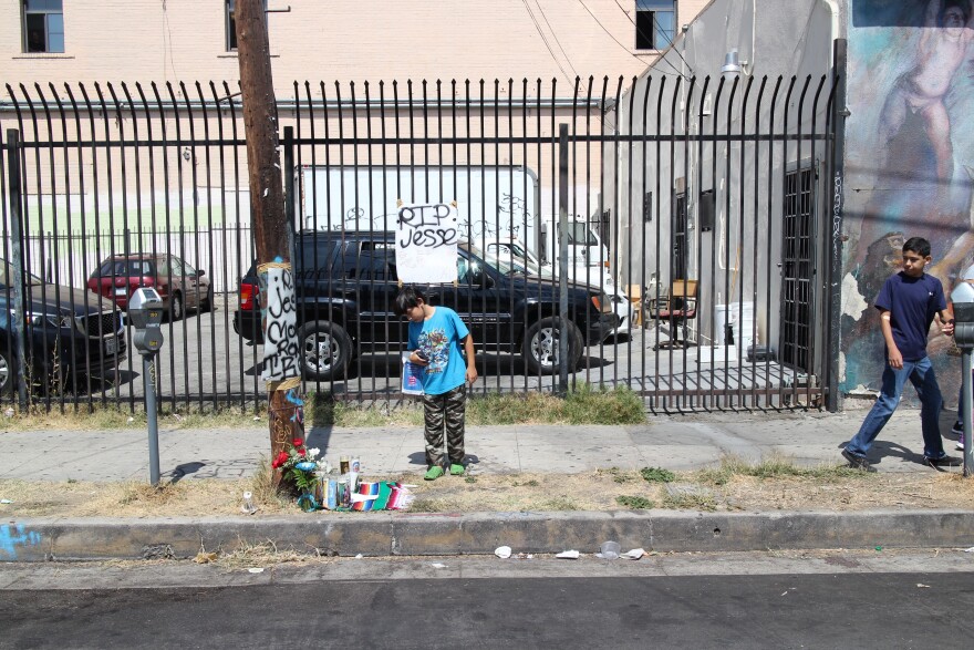 A boy stands over the memorial for 14-year-old Jesse Romero, who was shot and killed by police in Boyle Heights on Tuesday.