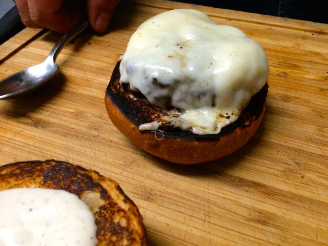 The beginnings of a truffle burger: a medium-rare patty cooked with muenster cheese.