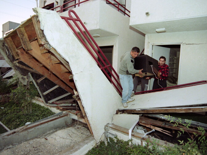 With help from a friend, Tigran Daniyelyan (L) carries his television from his apartment complex that was destroyed by the Northridge earthquake on Jan. 17, 1994.